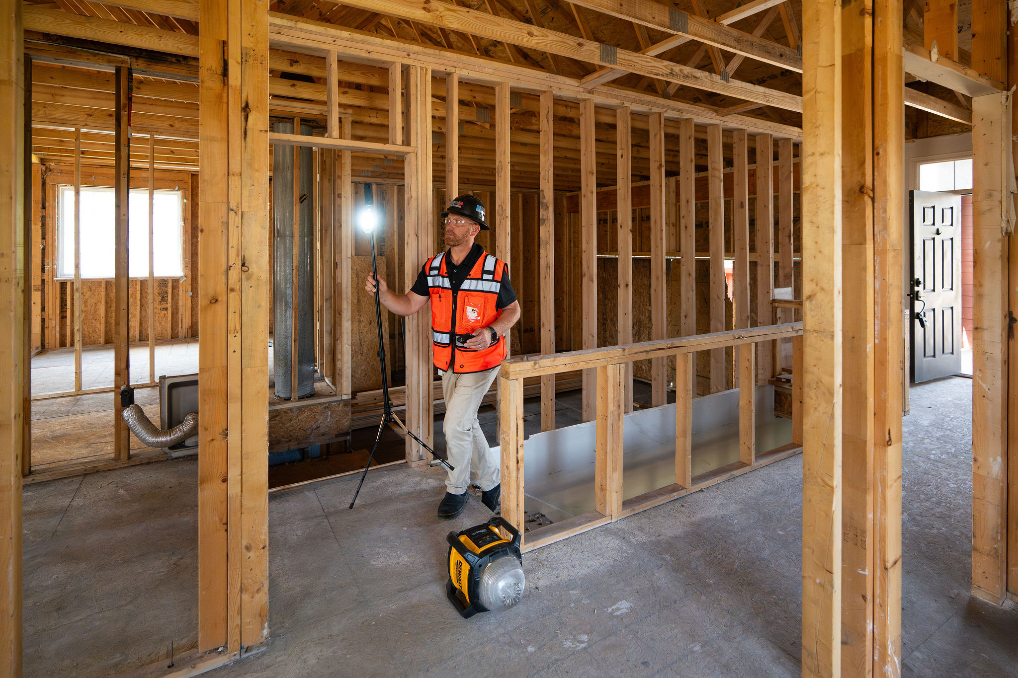 A person walks through a construction site with a 360 camera and light